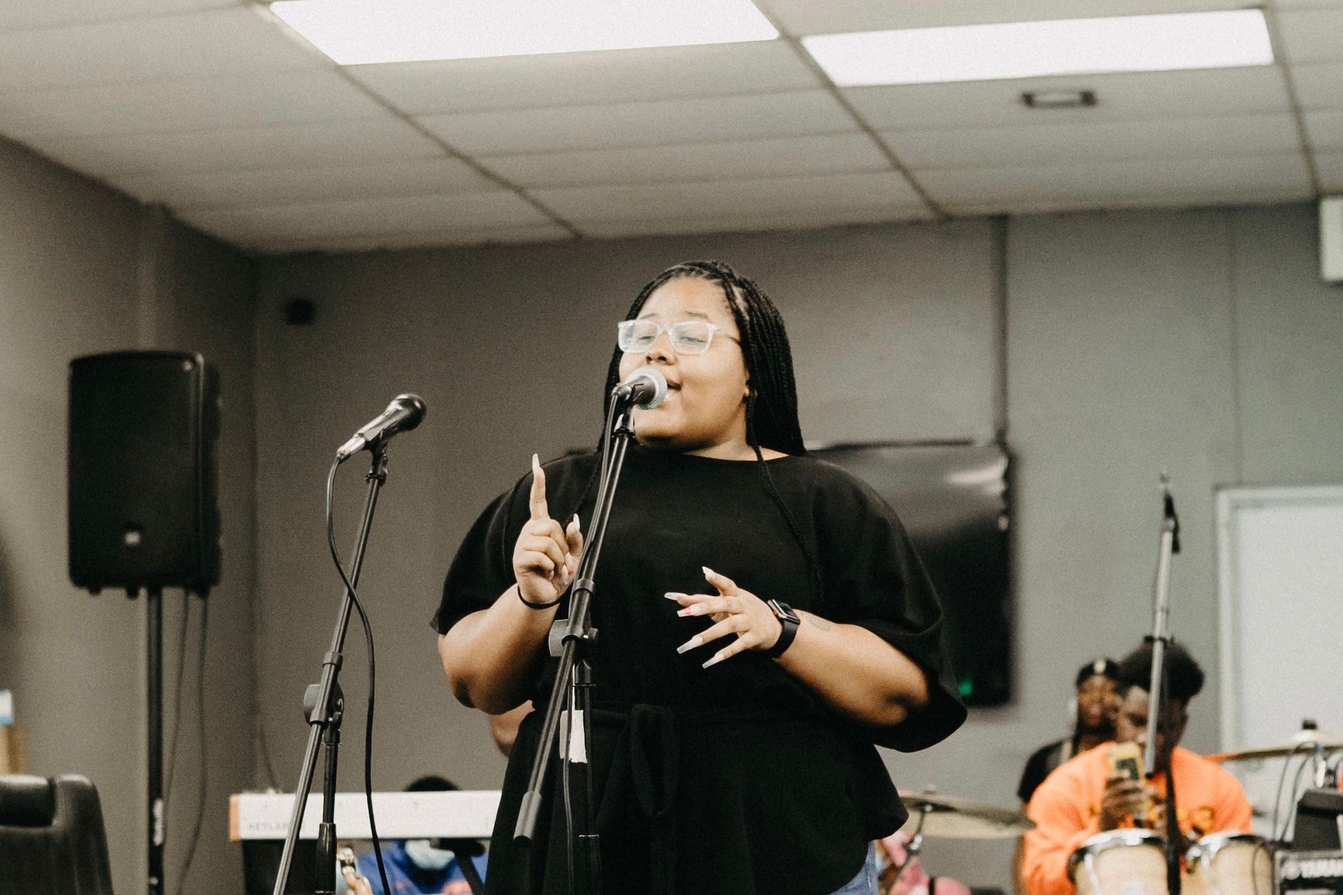 Black woman in a black t-shirt reading in an open mic event