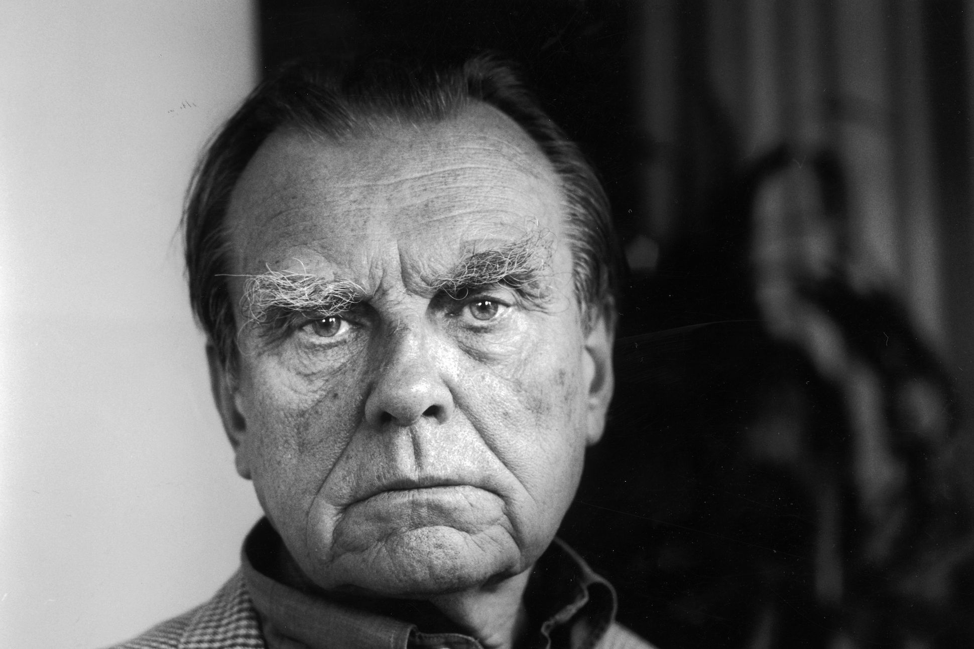 Headshot portrait of Polish author Czeslaw Milosz scowling.