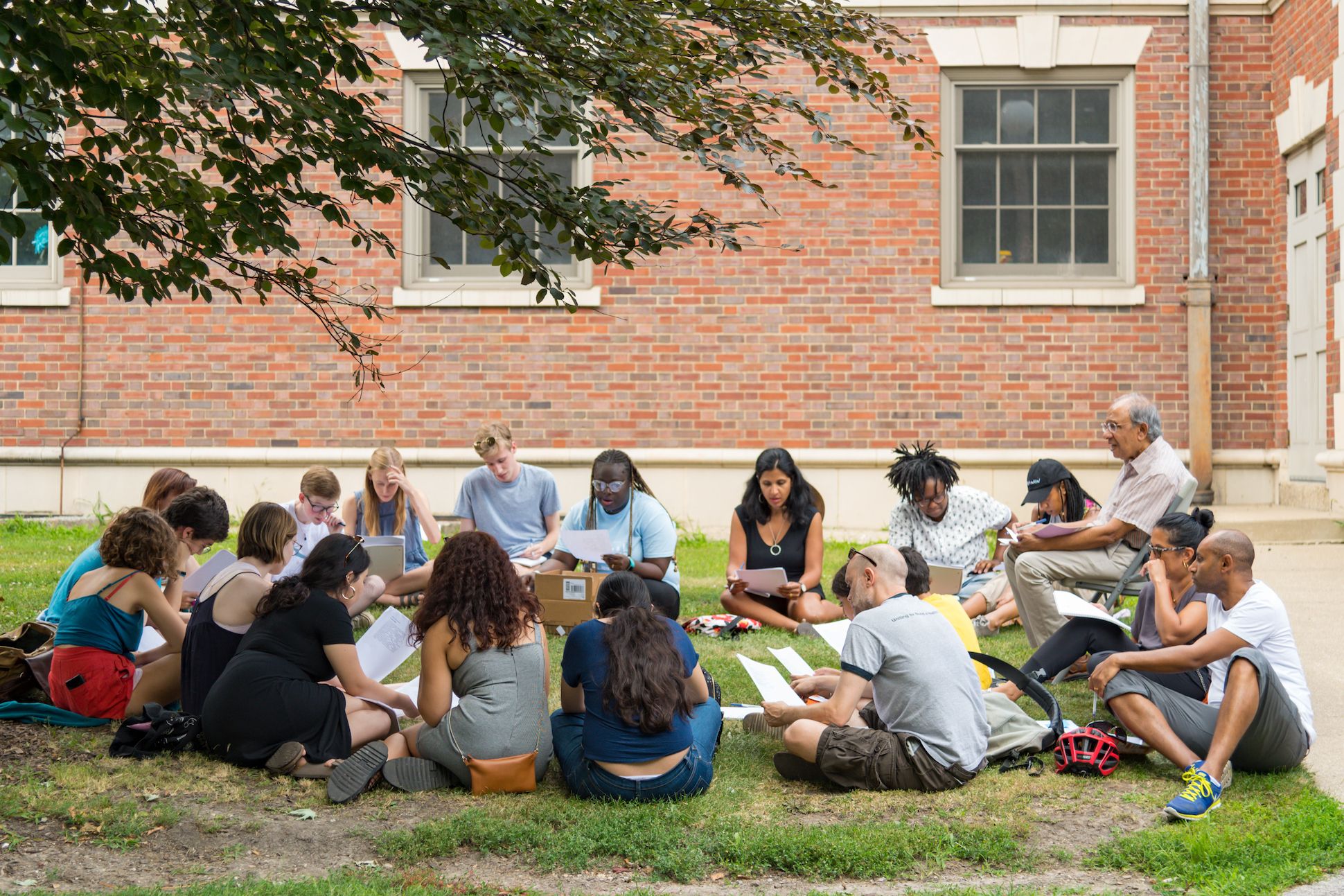 Image of a class gathered in a circle on the grass for discussion.