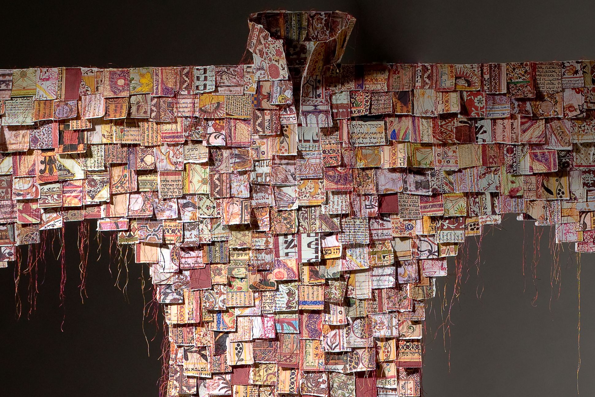 Photograph of a multicolored coat made of shredded marriage certificates.