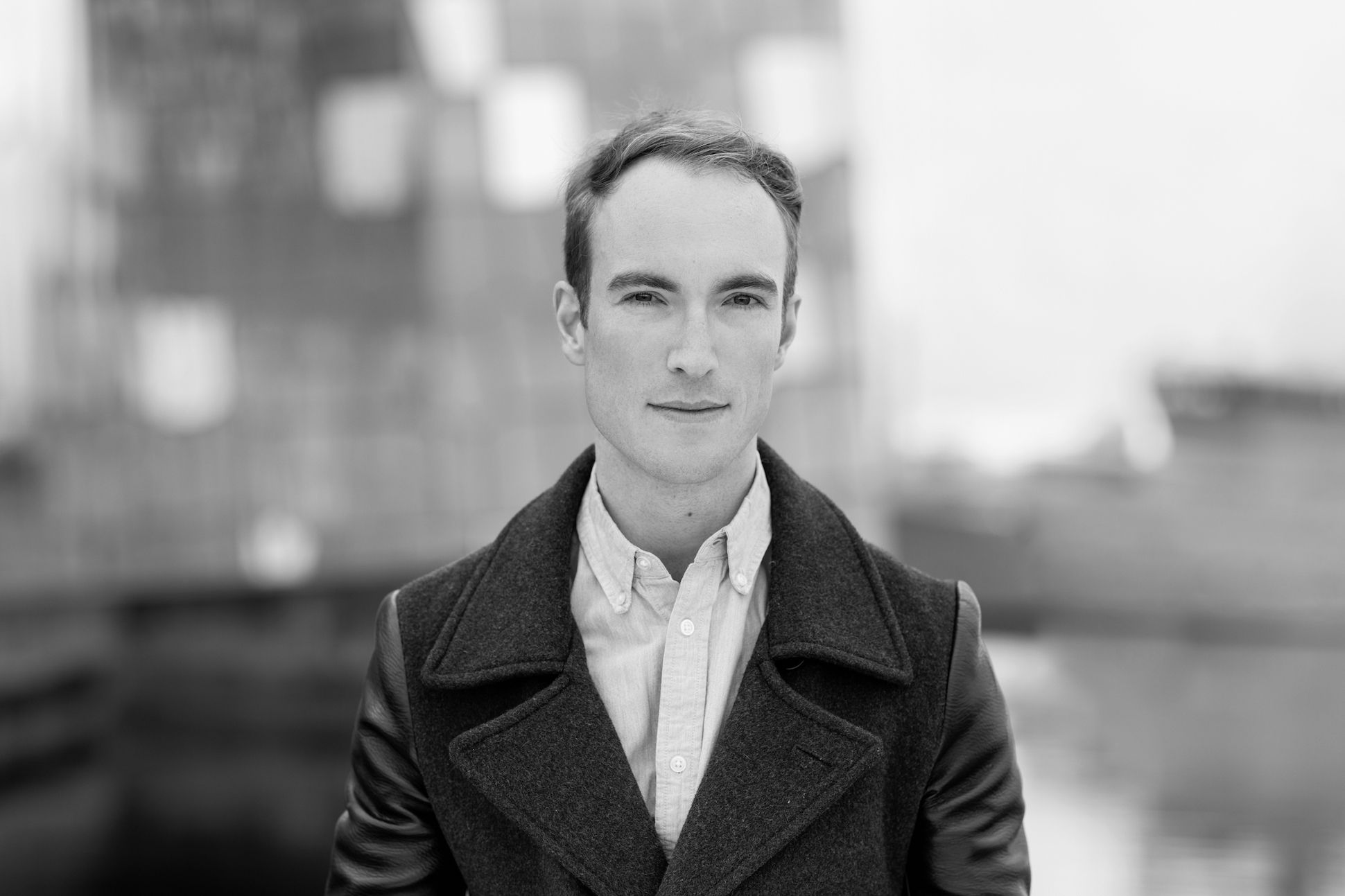 Black and white portrait of a man smiling with a coat