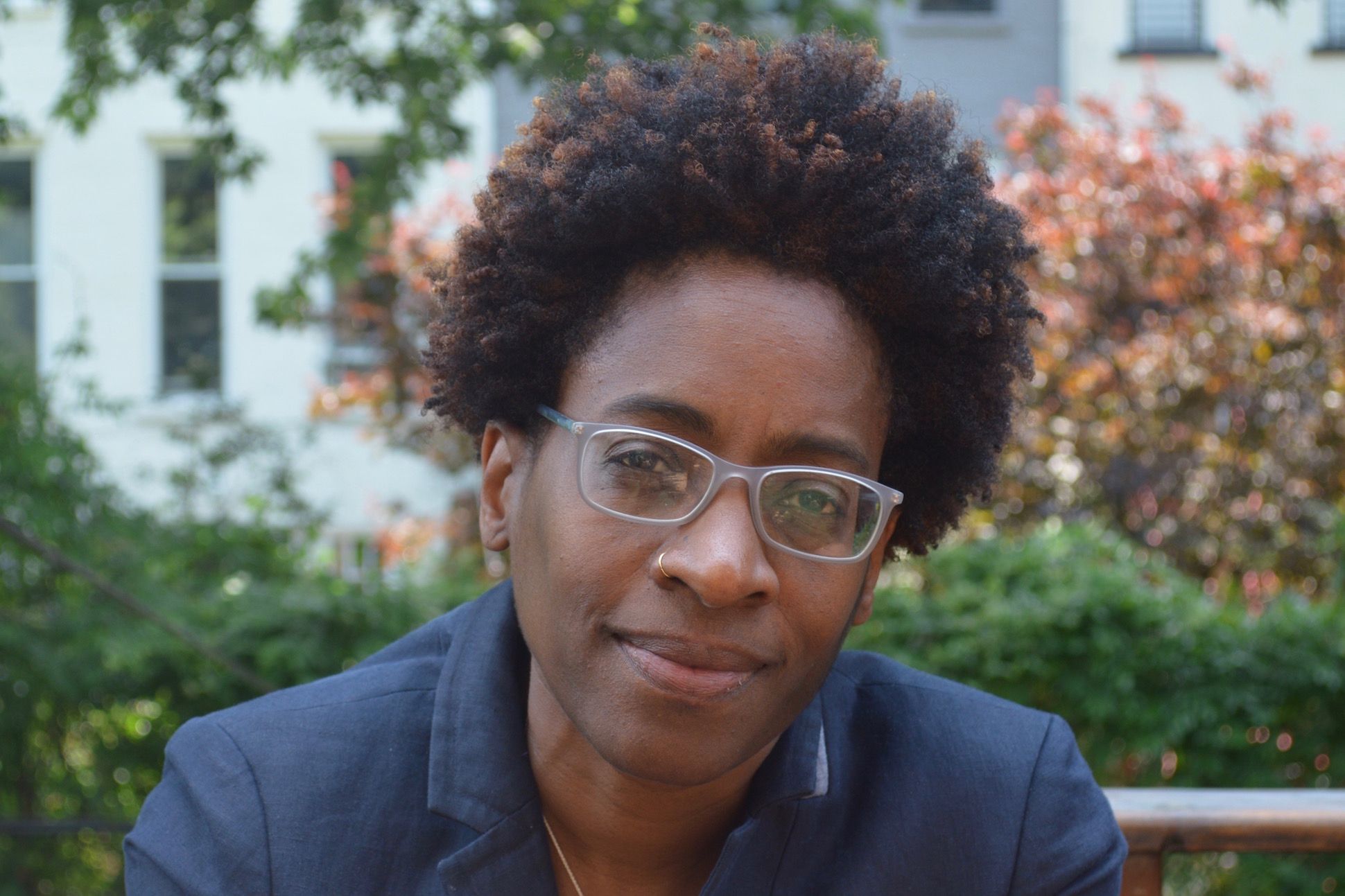 Writer Jacqueline Woodson sitting on a bench outdoors, cropped from the chest up.