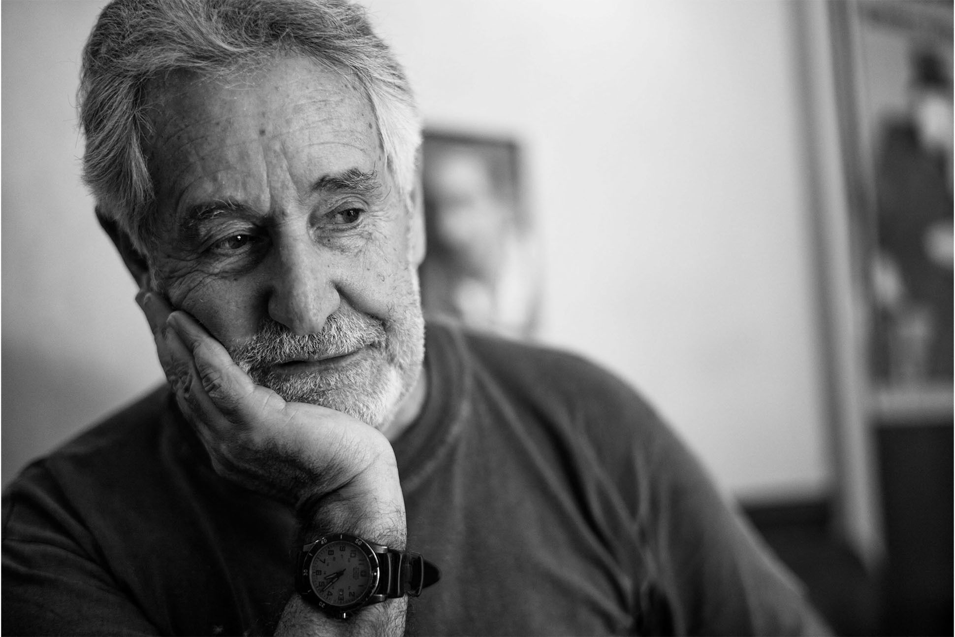 Photo of Breyten Breytenbach, chin resting in his right hand, as he looks down and away from the photographer.