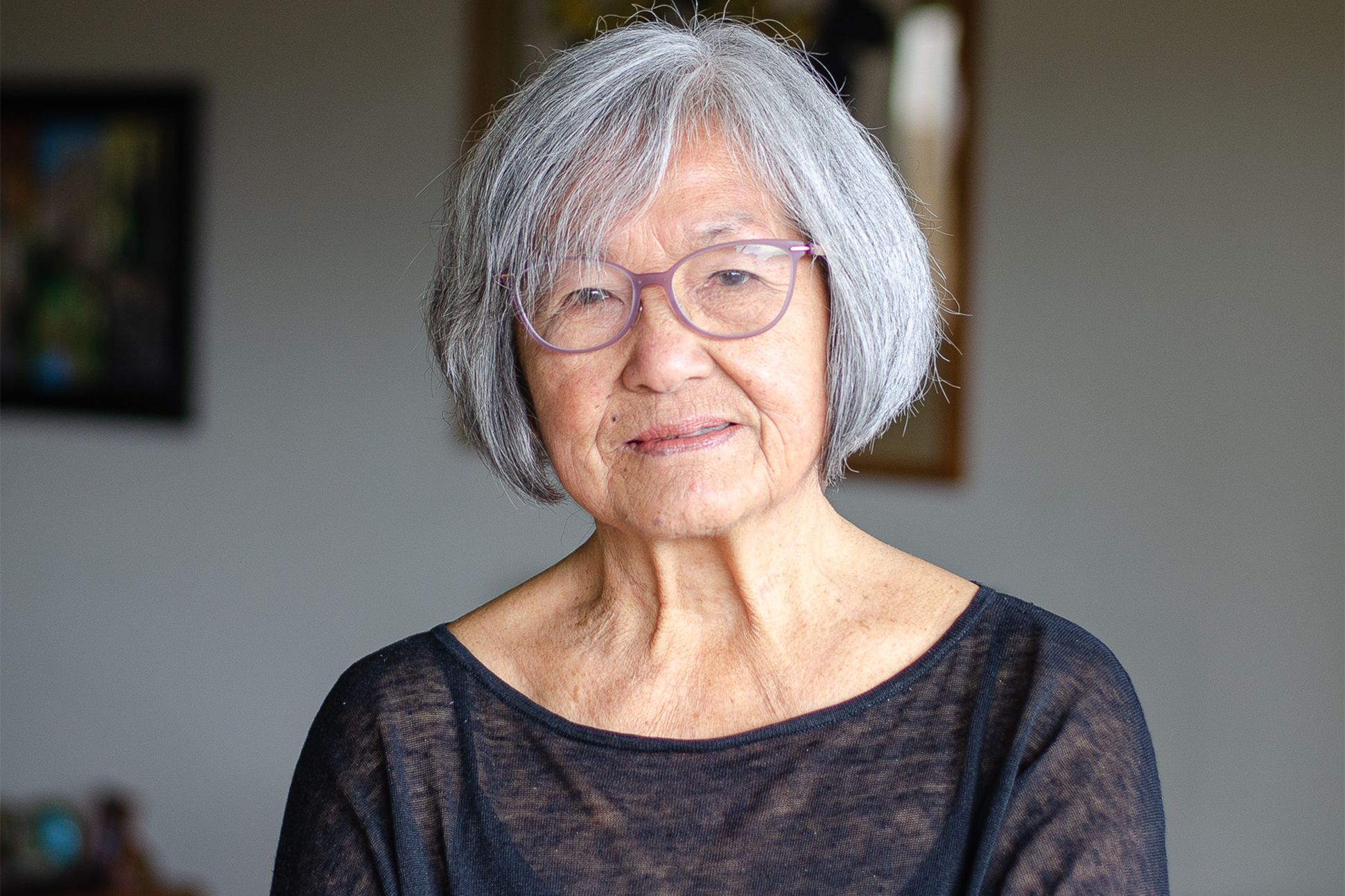 A photograph of Nellie Wong in a black shirt and eyeglasses, facing the camera.