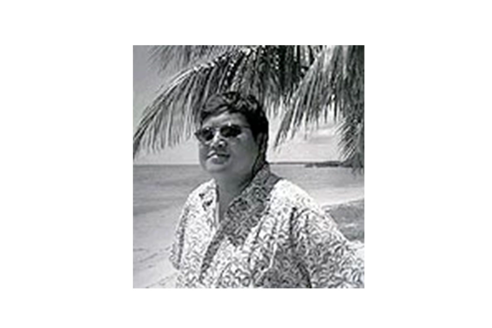 Black and white photo of Nick Carbó on a beach.