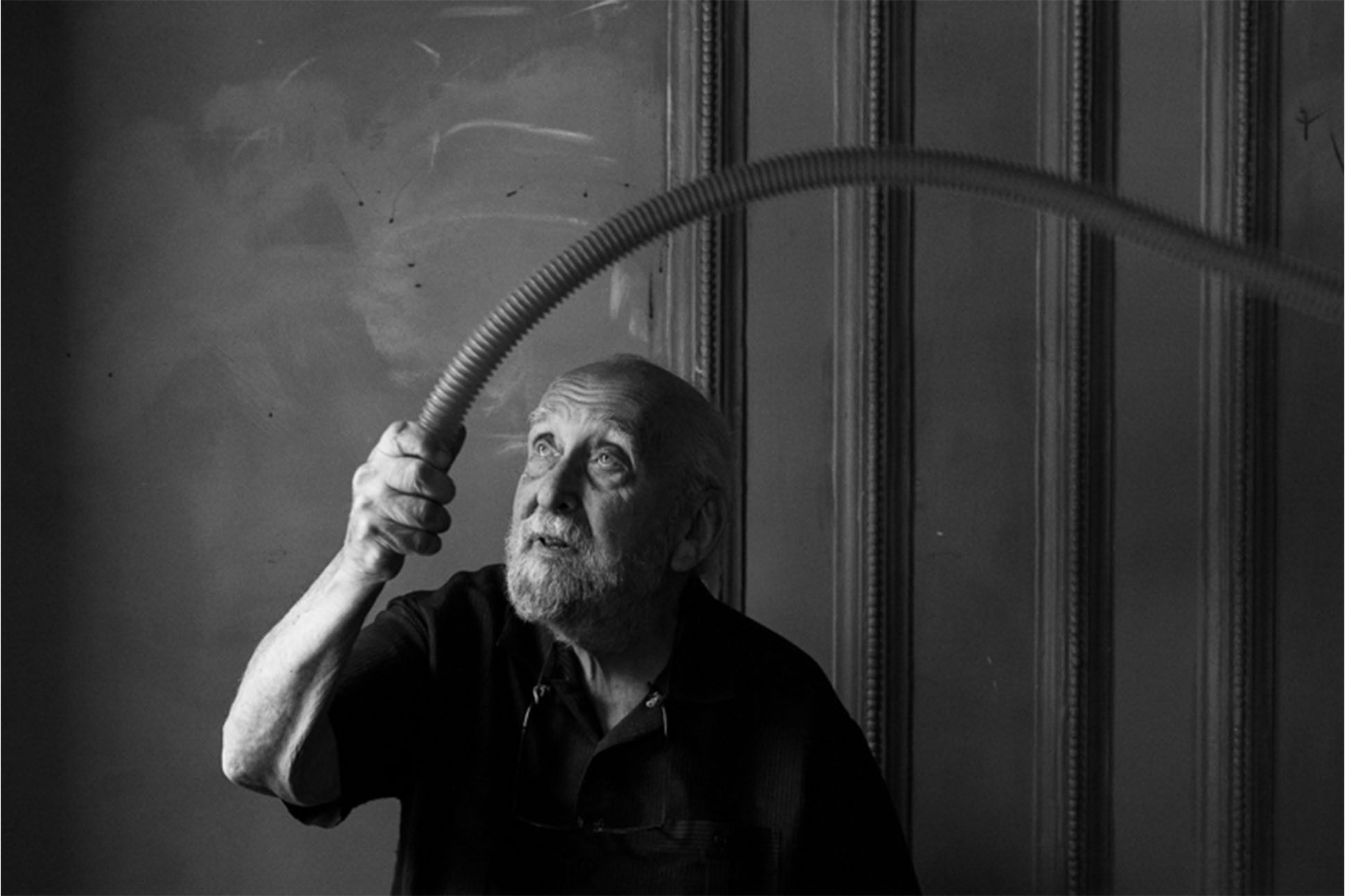Black and white photo of Rothenberg looking toward the sky while swinging a long horn-shaped object over his head.