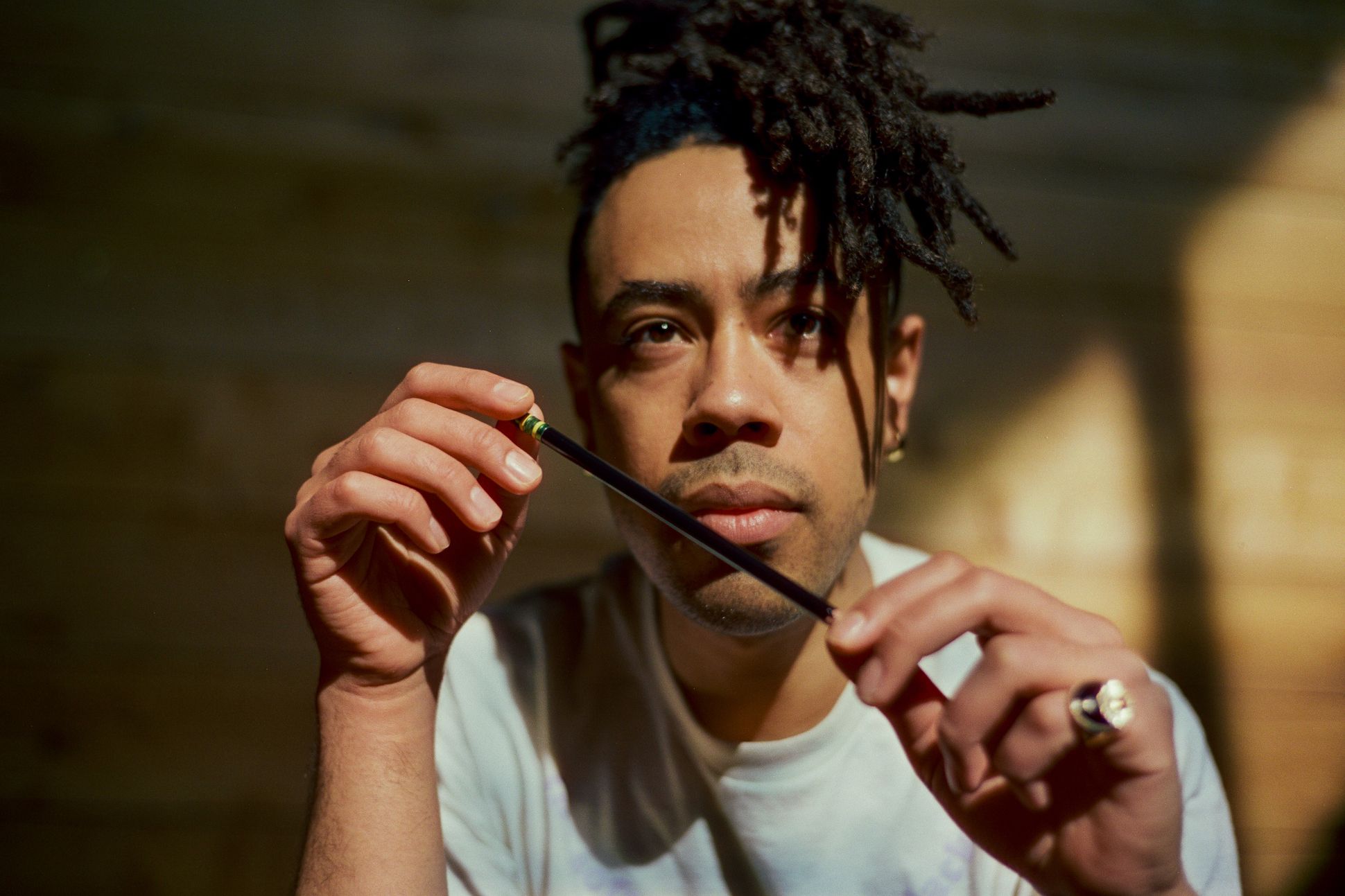 Headshot of poet Alan Pelaez Lopez holding a pencil