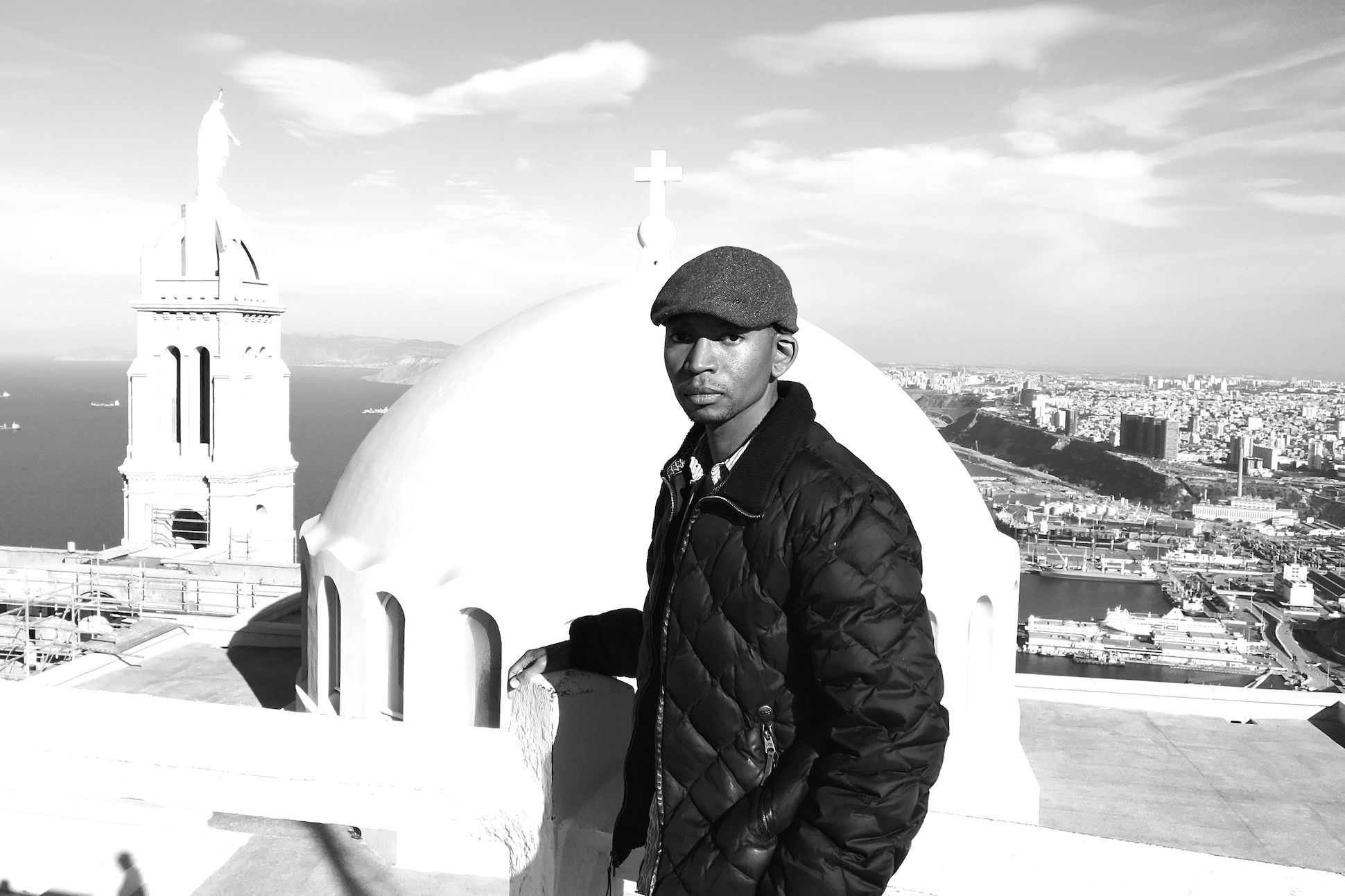 Headshot of poet Myronn Hardy standing on the roof of a cathedral building