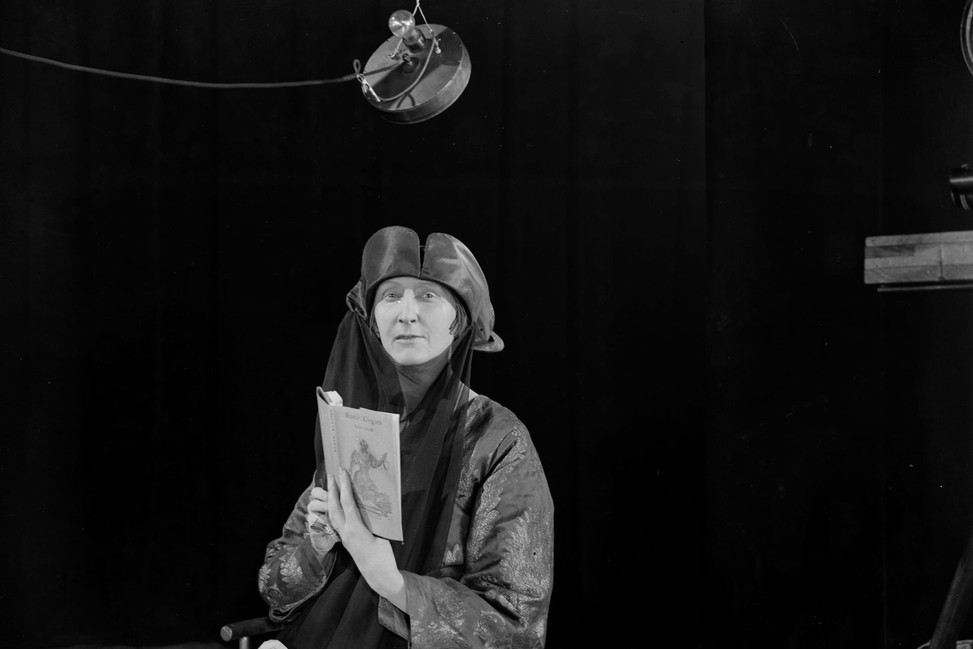 March 1927: Dame Edith Sitwell (1887 - 1964), poet and author who contravened the accepted poetic style of the day and introduced different rhythms based on jazz and dance music, reading from a book at Chronofilm Studios.