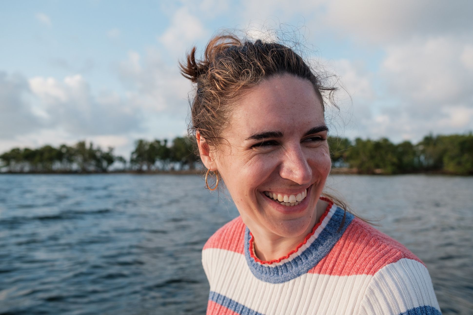 Woman in a sweater with red, white, blue stripes by a river