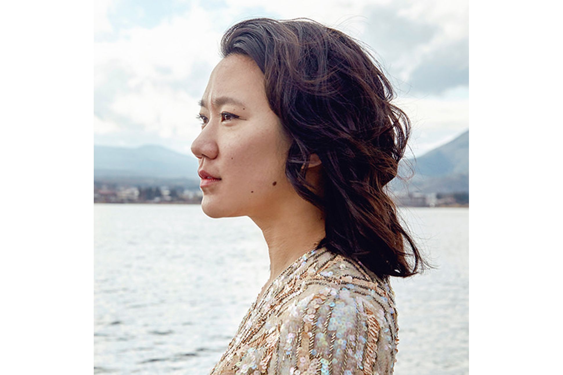 Asian woman with short curly hair standing by the sea