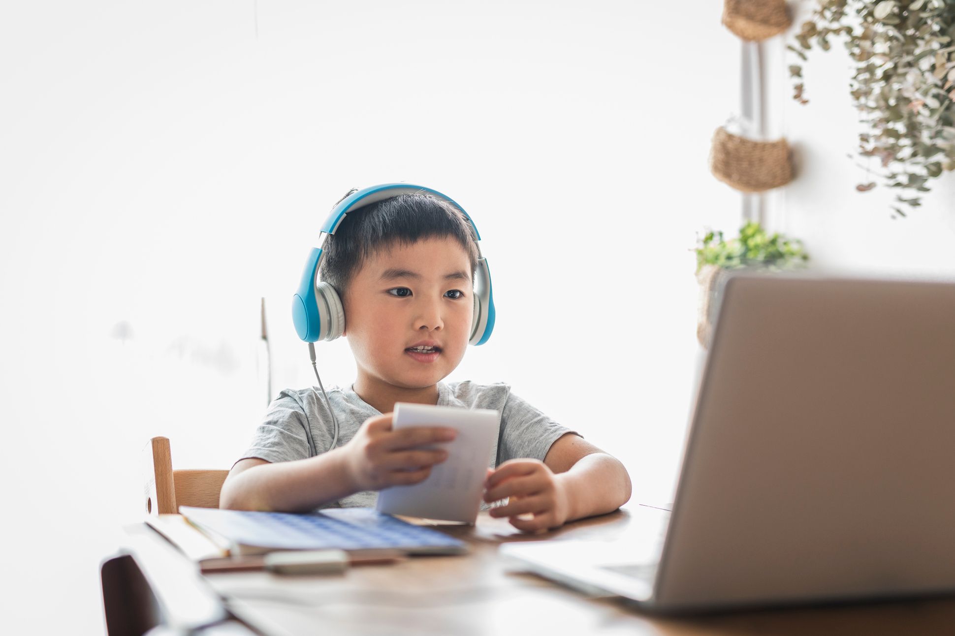 Boy is attending online class room in the living room.
