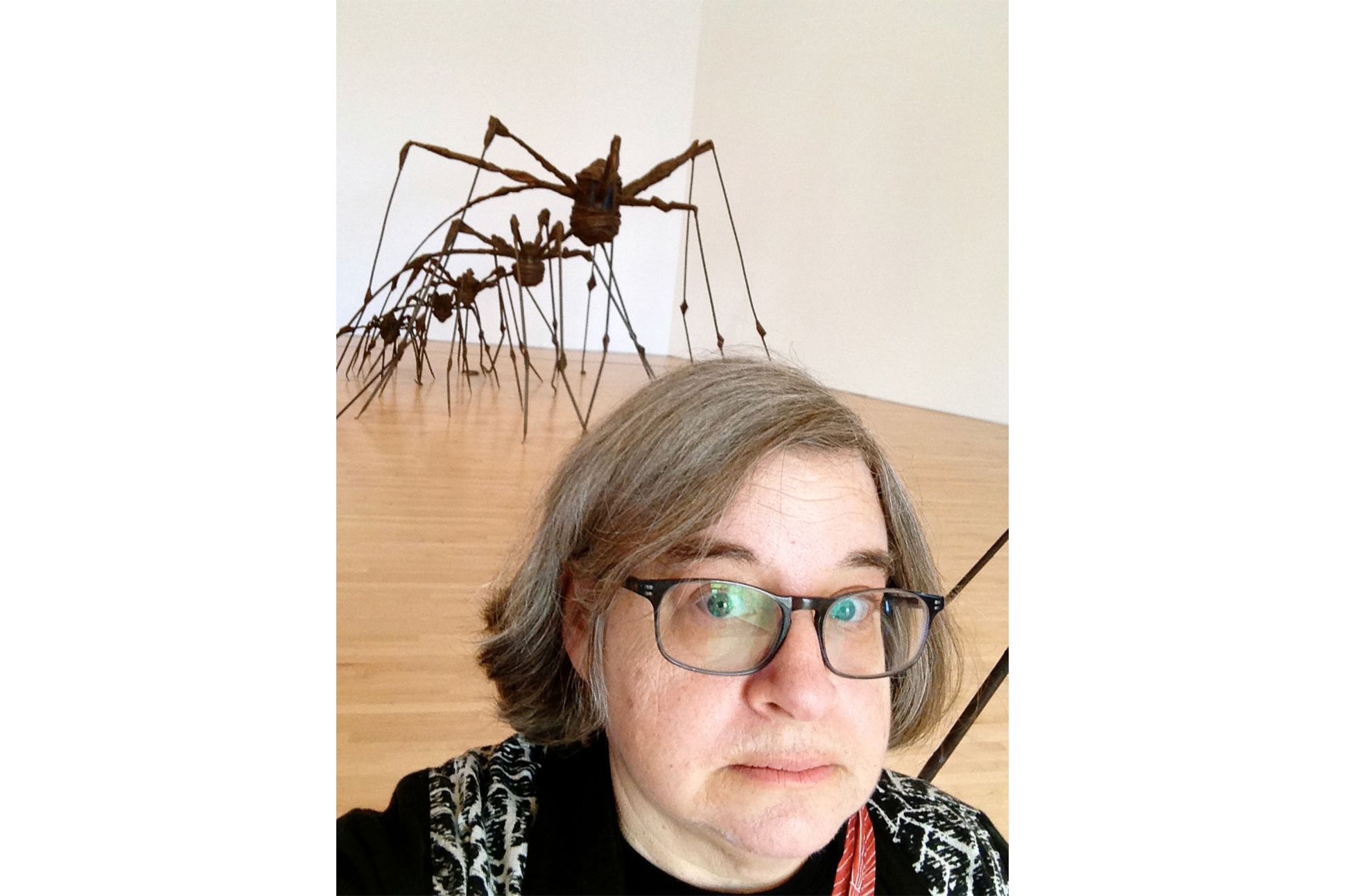 Poet Carol Dorf posing with Louise Bourgeois's spider sculpture in the background