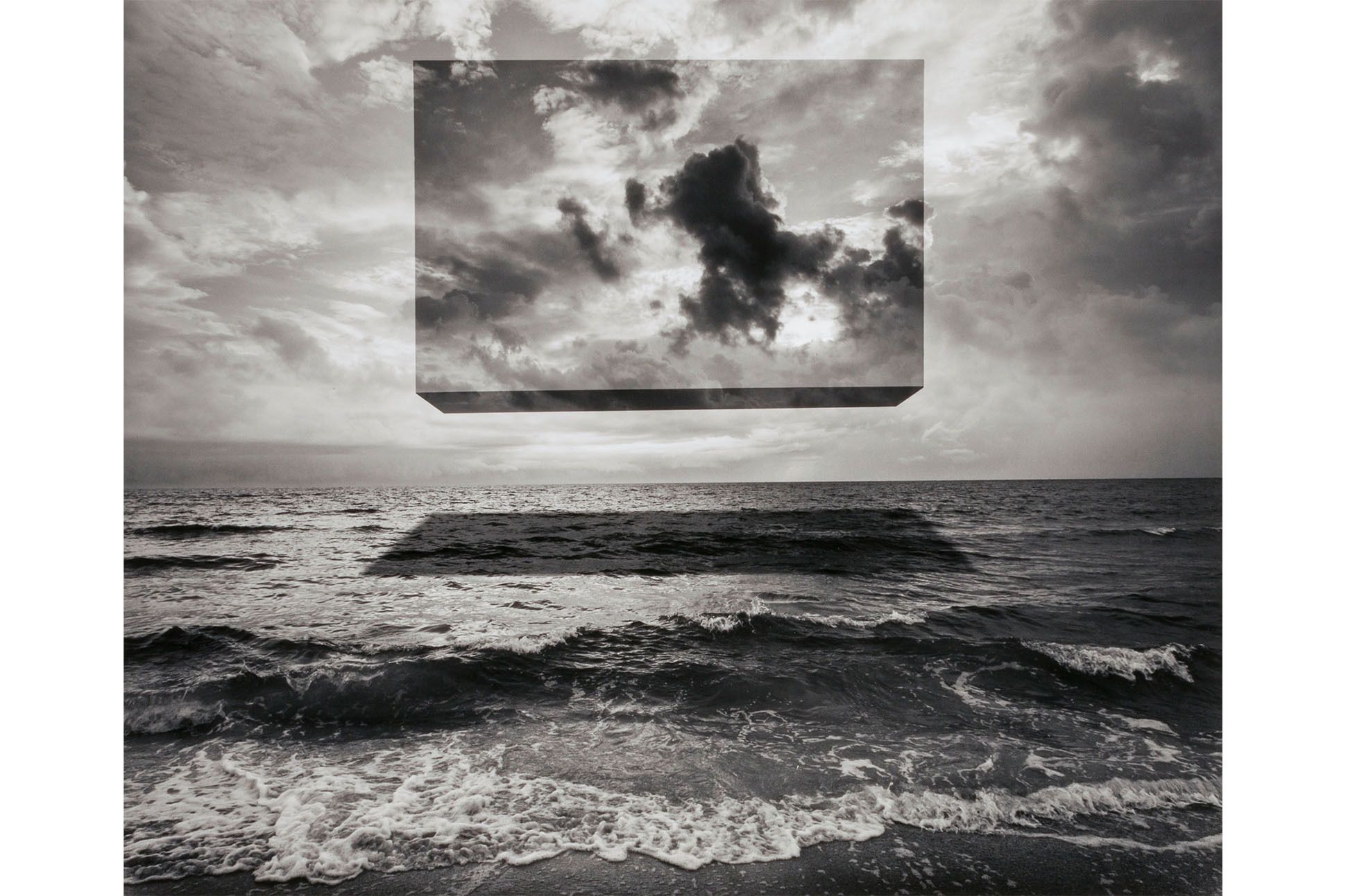 Gelatin silver print featuring up close of ocean waves beneath a cloud-filled sky, with a rectangular shape superimposed on the sky magnifying the clouds and leaving a shadow on the waves.