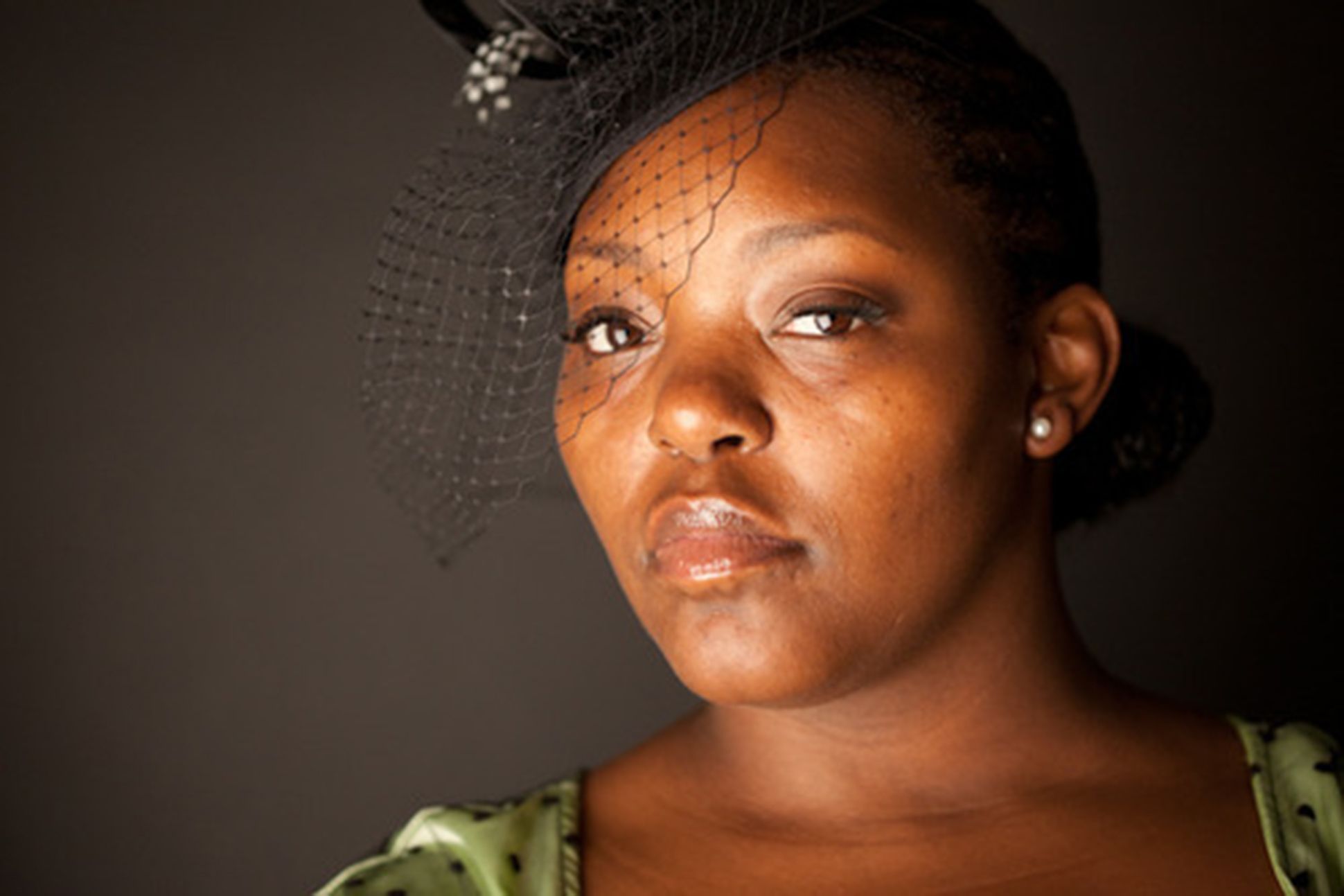Image of Mahogany L Browne wearing a fascinator in front of a dark background.