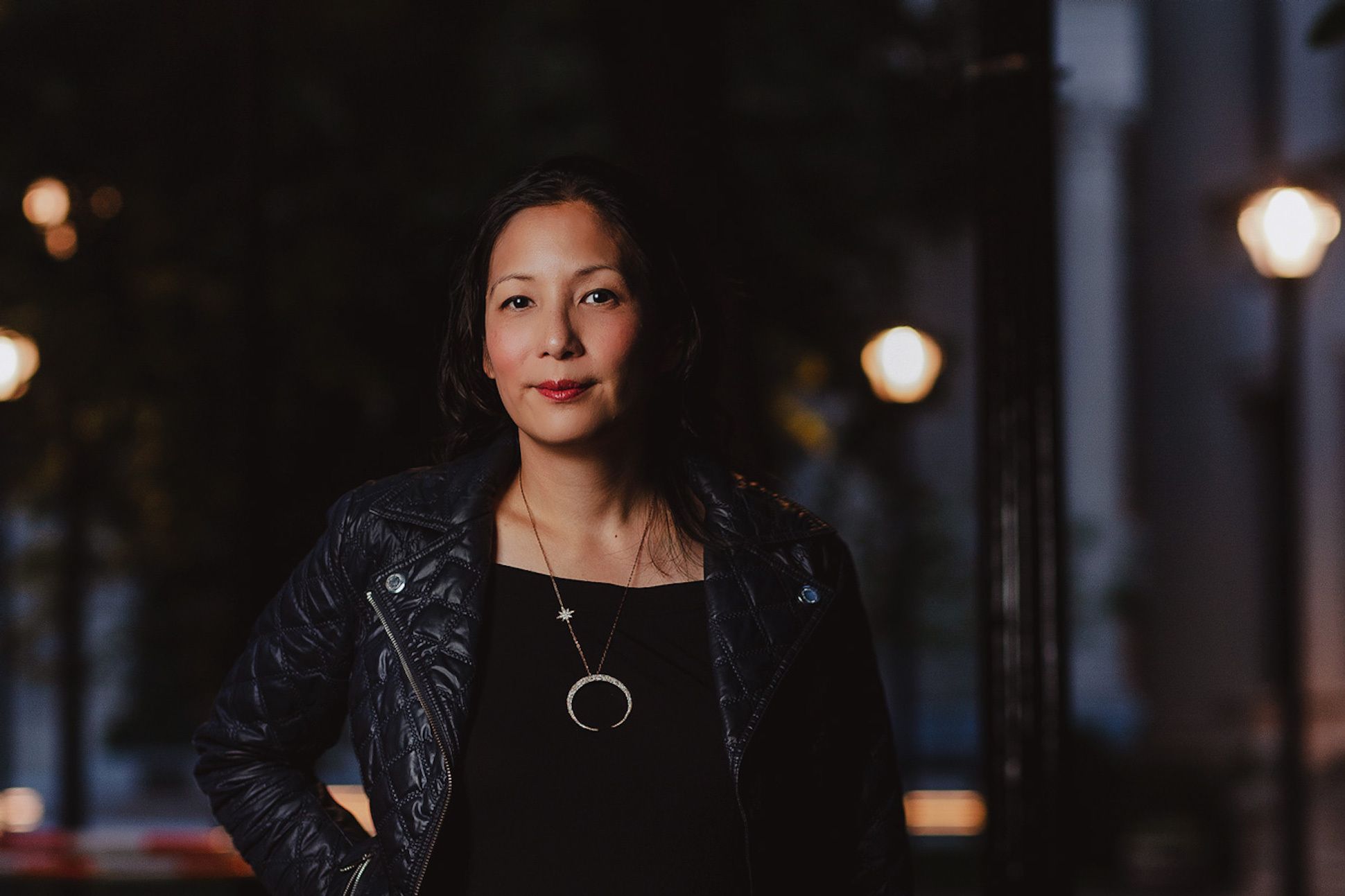Asian woman in a black jacket in the nighttime of city