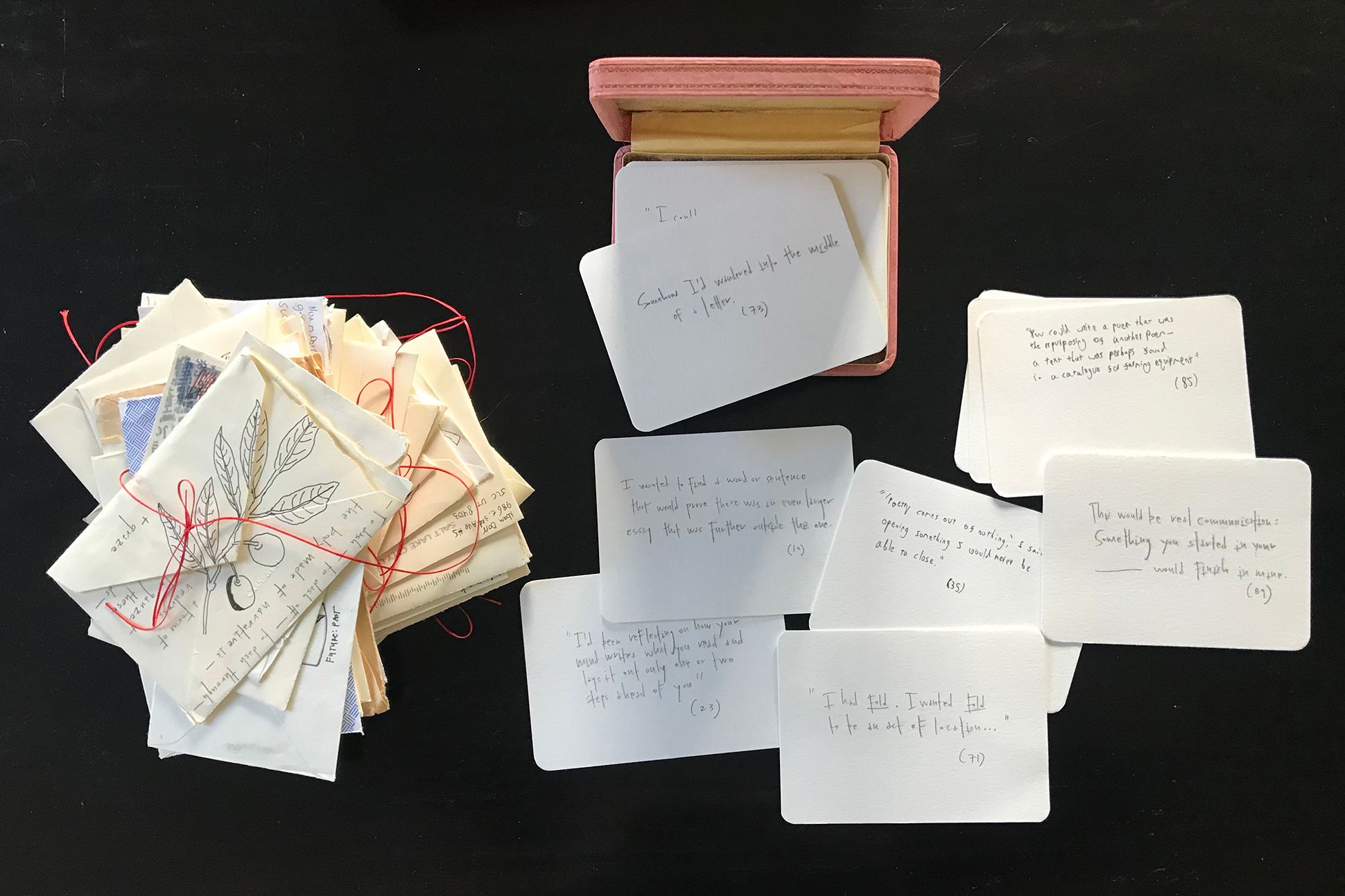 Photo from above of handwritten text on white, notecard-sized paper and on letters which are bound with red string