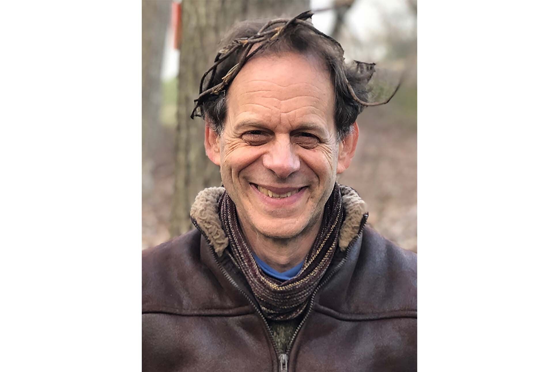 Headshot of poet Mark Schafer wearing a crown of branches