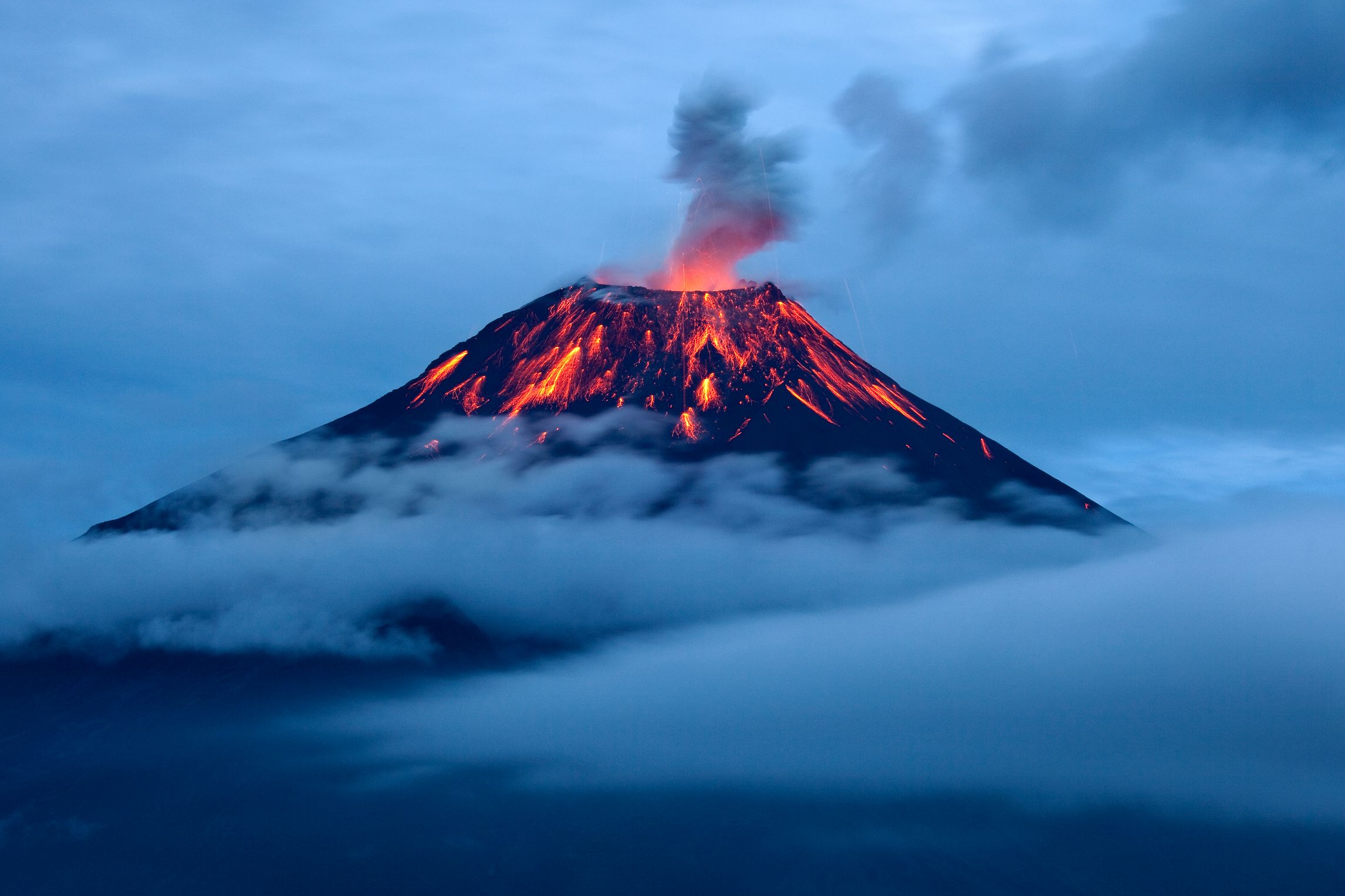 Eruption of tungurahua volcano at dusk with lava flows.