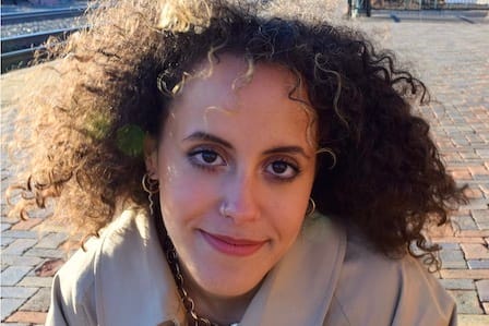 A woman with curly hair and jacket smiling