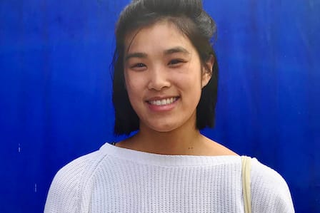 An Asian woman smiling in front of a blue background