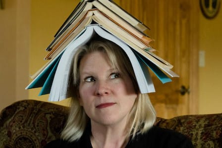 Headshot of poet Laura Weldon with a pile of books on her head