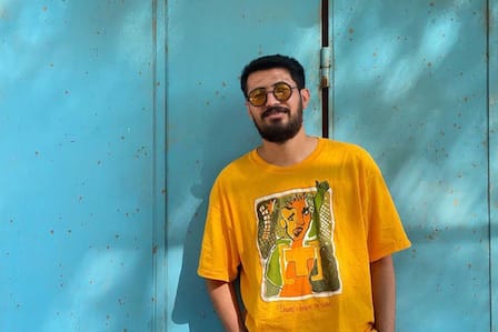 A man with yellow sunglasses and t-shirt in front of a blue door