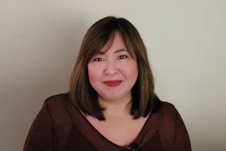 A woman with mid-length hair in a maroon blouse