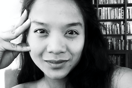A long hair Asian woman in front of a bookshelf