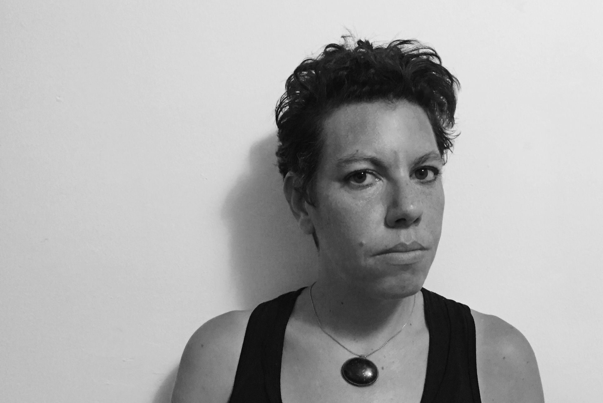 Woman posing with a black tank top and black stone necklace.