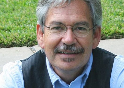 Headshot of poet Benjamin Alire Saenz outdoors.
